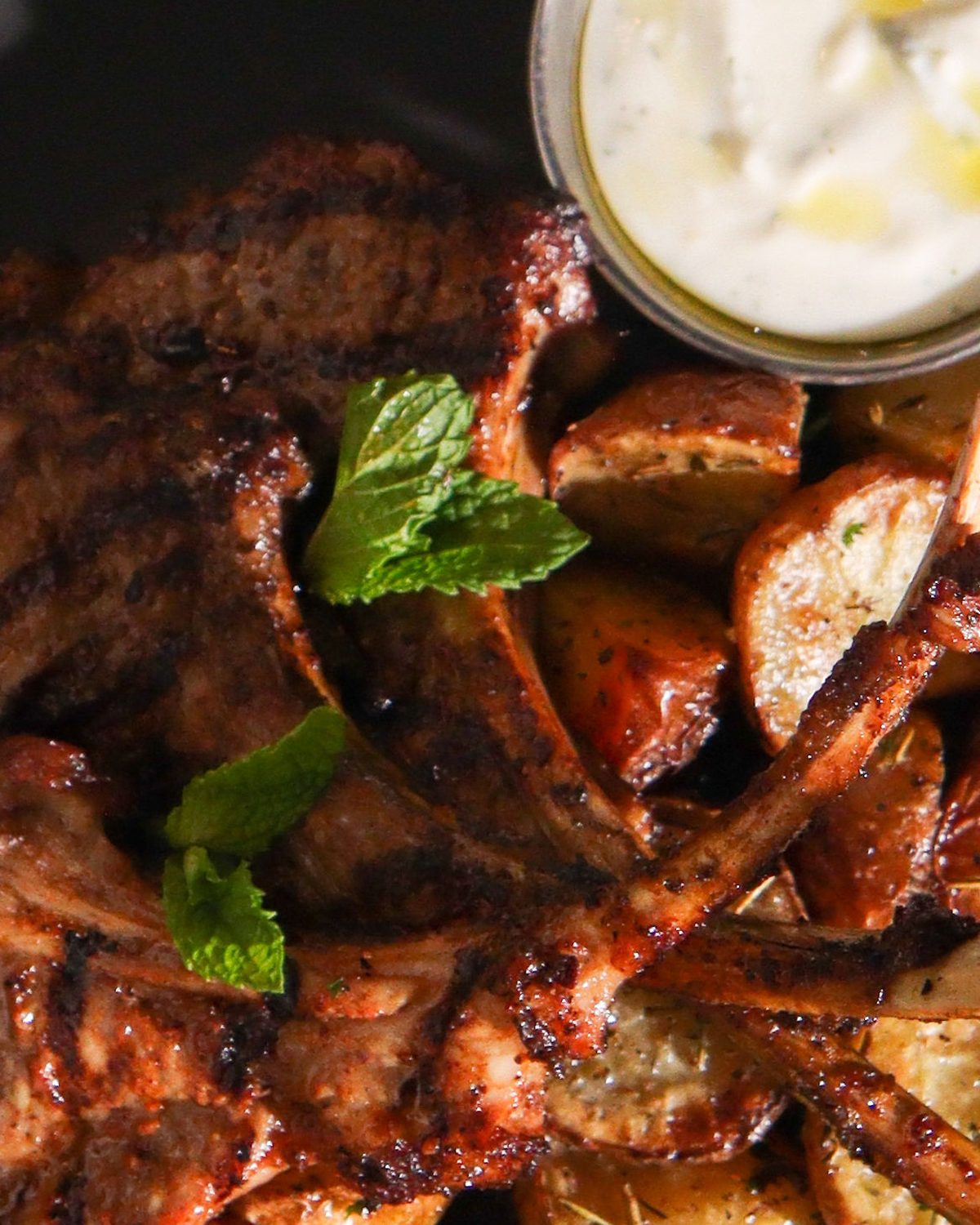 Close view of charred lamb chops and roasted potatoes