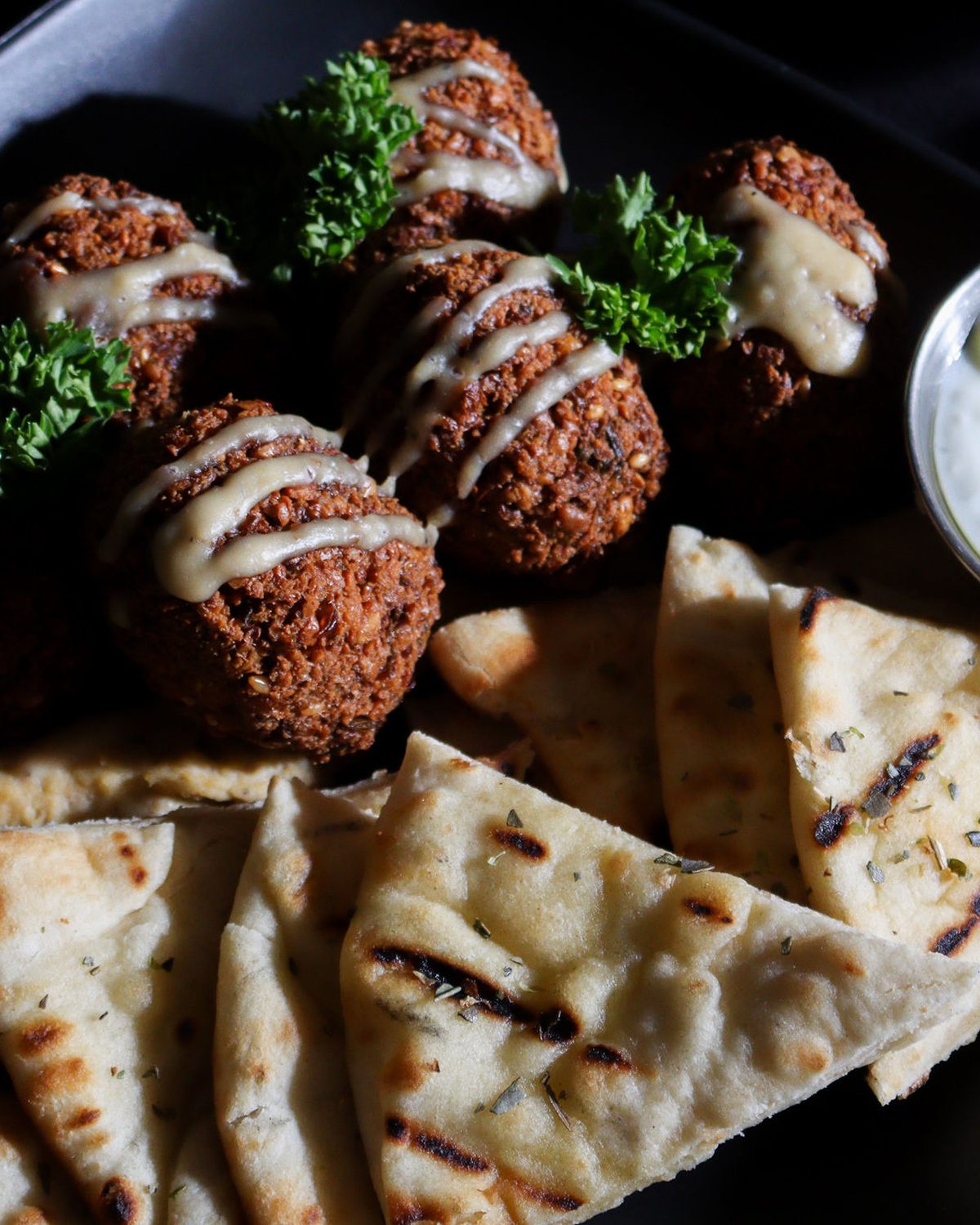 Falafel platter plated on matte black with tzatziki