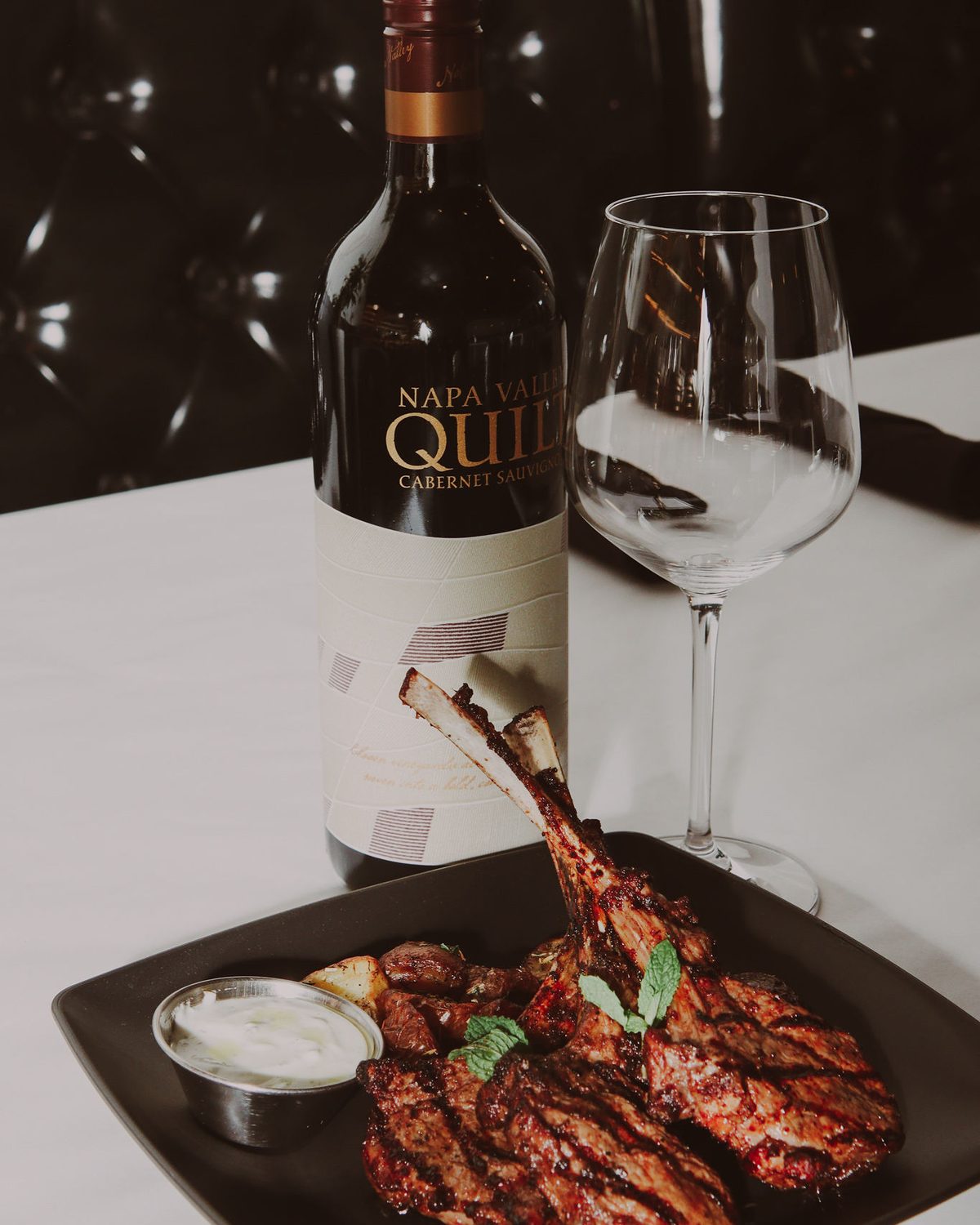 Lamb chops plated beside a bottle of Cabernet