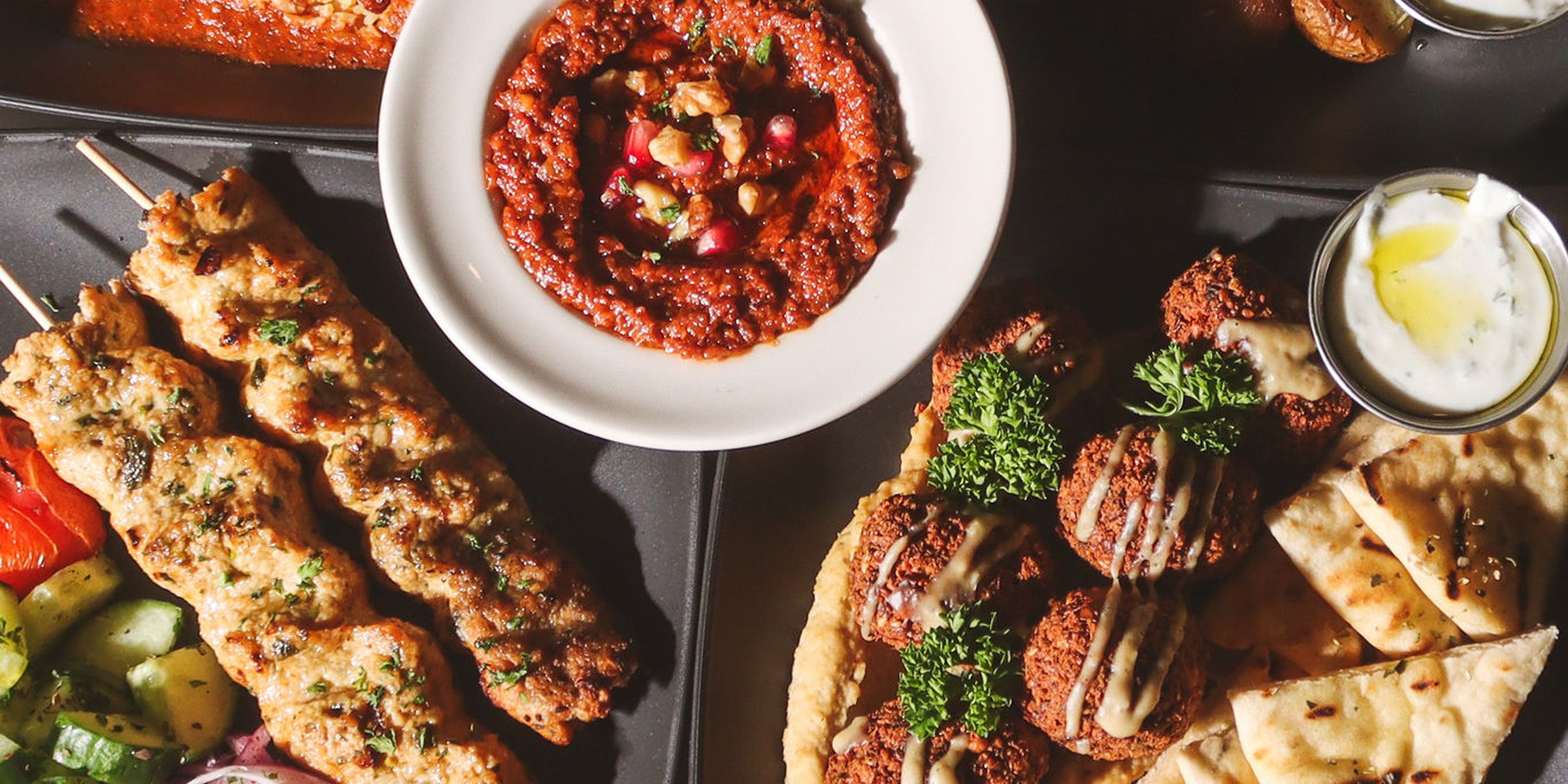 A full Fusion table laid with kabobs, mezze and warm pita