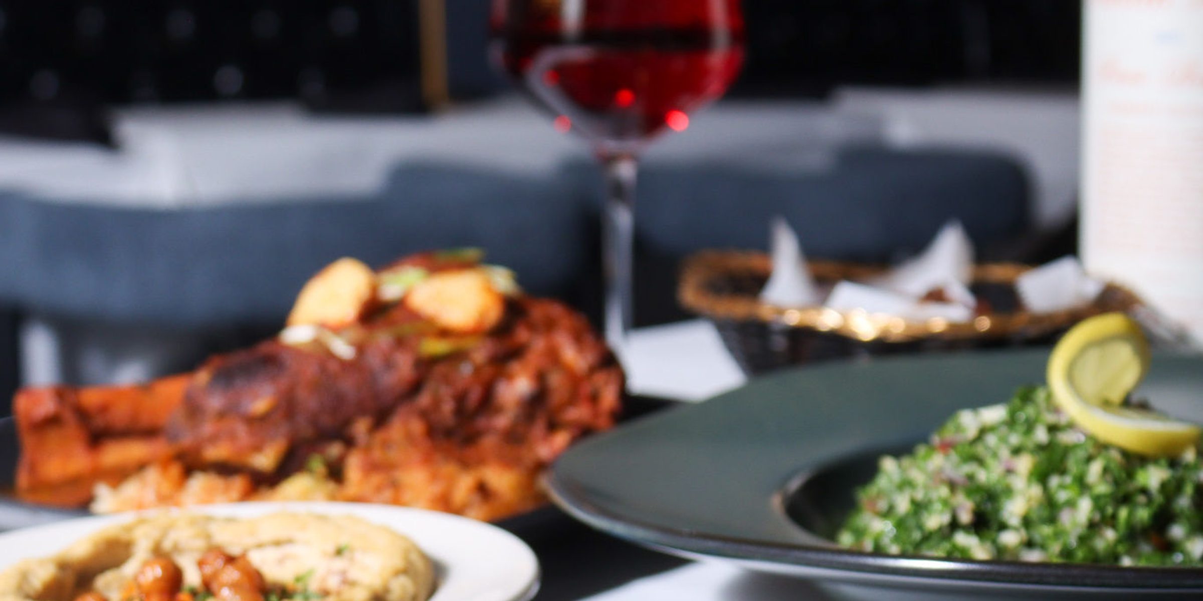 A corner table set with wine and dinner